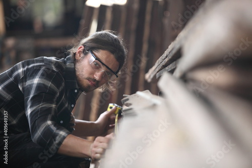 Carpenter, joiner is working in the workshop. Man at work on wood.Image of mature carpenter in the workshop,furniture making concept.