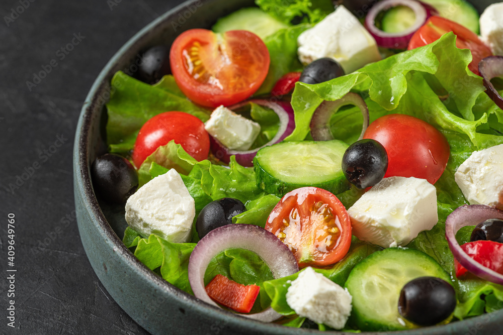 Close up of Greek salad with fresh vegetables, feta cheese and olives in a plate on black background. Vegetarian food Close up of Greek salad with fresh vegetables, feta cheese and olives in a plate on black background. Vegetarian food