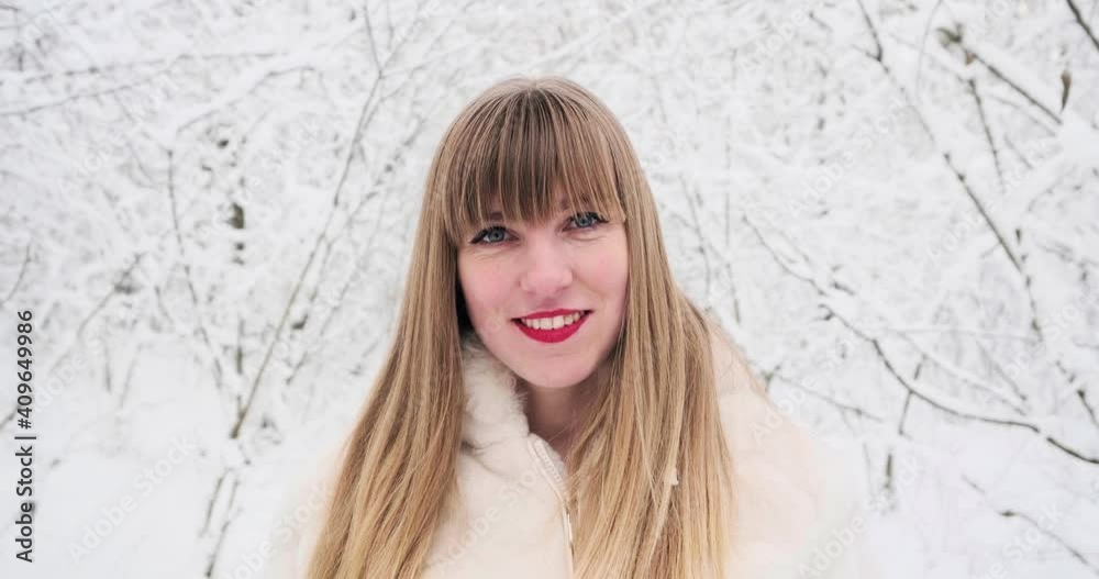 Beautiful smiling confident young white woman pretty face looking at camera posing alone at snowy forest Beautiful smiling confident young white woman pretty face looking at camera posing alone at snowy forest