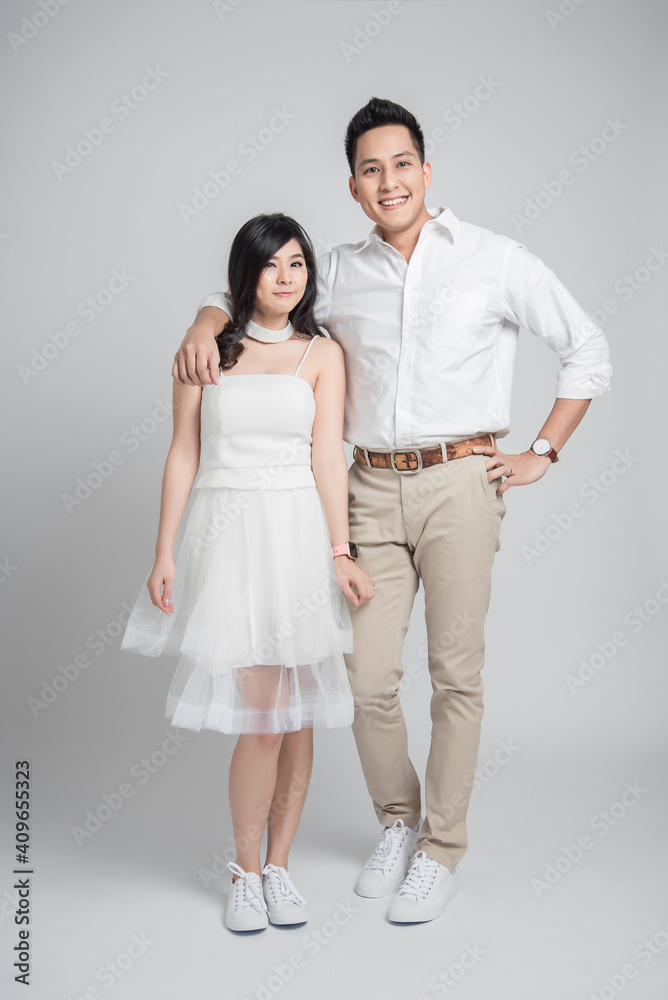 Happy couple Asian groom embracing his bride in casual wedding dress standing on white background Happy couple Asian groom embracing his bride in casual wedding dress standing on white background