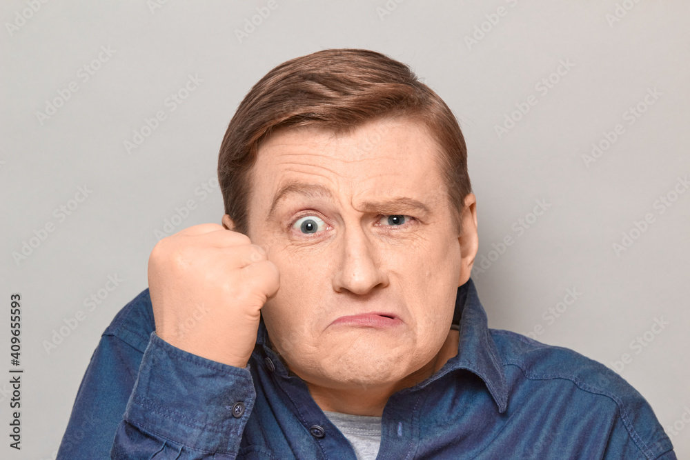 Portrait of angry disgruntled man shaking fist in threatening gesture Portrait of angry disgruntled man shaking fist in threatening gesture