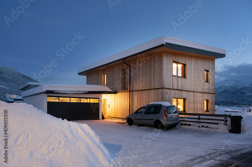 View of single-family house with garage in snow-covered winter with cleared entrance at night © A2LE