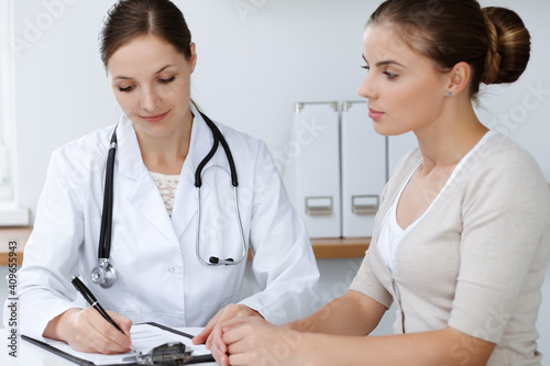 Doctor and patient are sitting and discussing health examination results in clinic office. Health care, medicine and good news concepts