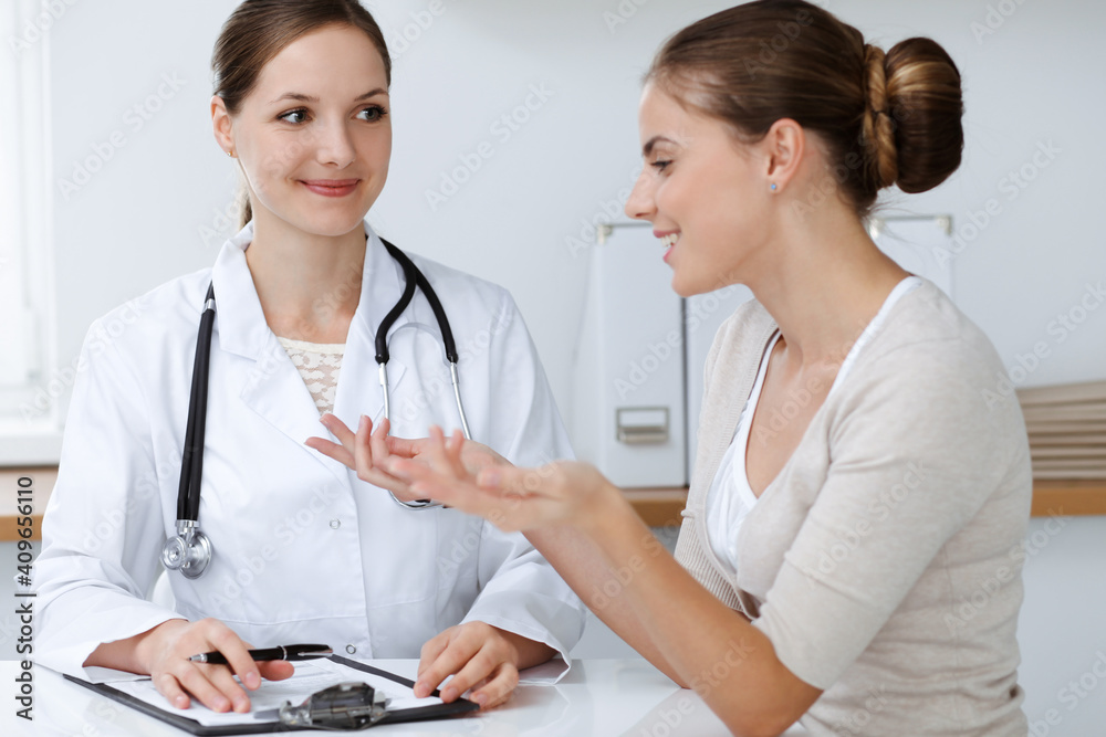 Doctor and patient are sitting and discussing health examination results in clinic office. Health care, medicine and good news concepts Doctor and patient are sitting and discussing health examination results in clinic office. Health care, medicine and good news concepts