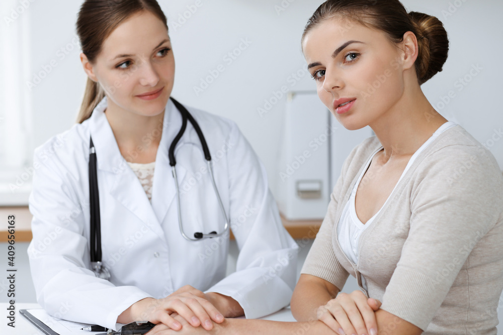 Doctor and patient are sitting and discussing health examination results in clinic office. Health care, medicine and good news concepts Doctor and patient are sitting and discussing health examination results in clinic office. Health care, medicine and good news concepts