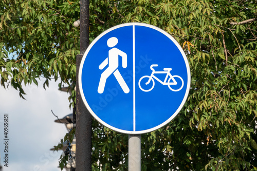 Bicycle path sign on a background of green foliage and blue sky. Close-up.