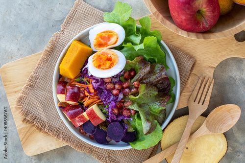 Healthy salad of fresh vegetables - egg, carrot, purple cabbage, pumpkin, apple, purple sweet potato and pomegranate on a bowl. Healthy breakfast. Flat lay. Top view.