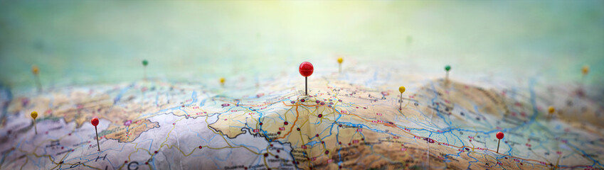 Pins on a geographic map curved like mountains. Pinning a location on a map with mountains. Adventure,  geography, mountaineering, hike and travel concept background.