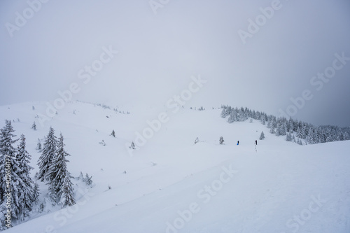 Obraz na płótnie Group of hikers climbing up snowy Ciucas mountains in foggy weather in winter w salonie