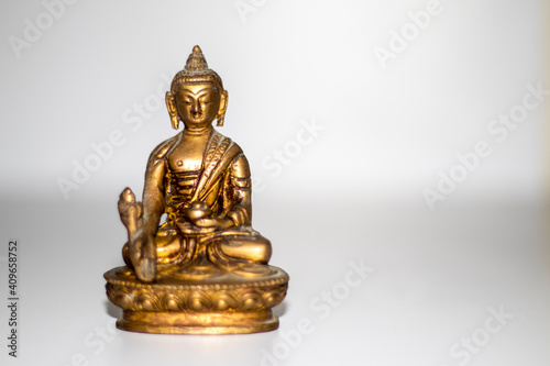 Close up shot of a bronze buddha mini statue. Indoors