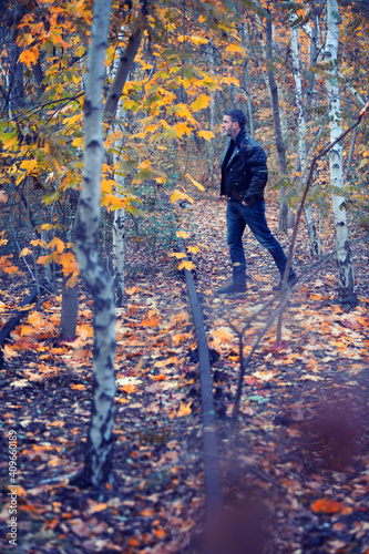 man in black leather jacket walking in forest