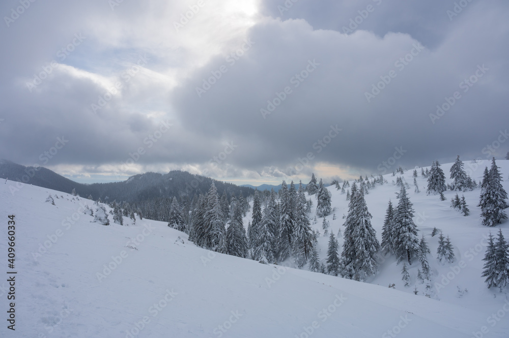 View over snow covered Romanian mountains near Brasov during a cloudy day in winter