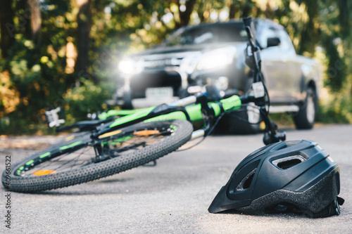 Close-up of a bicycling helmet fallen on the asphalt next to a bicycle after car accident on the road. Conceptual of accident car crash with bicycle on road.