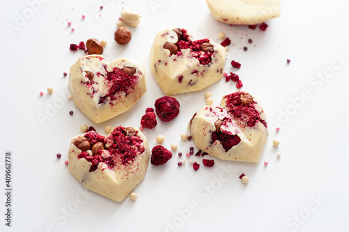 chocolate candies, in the form of hearts with white chocolate with raspberries, handmade, top view, on a white background