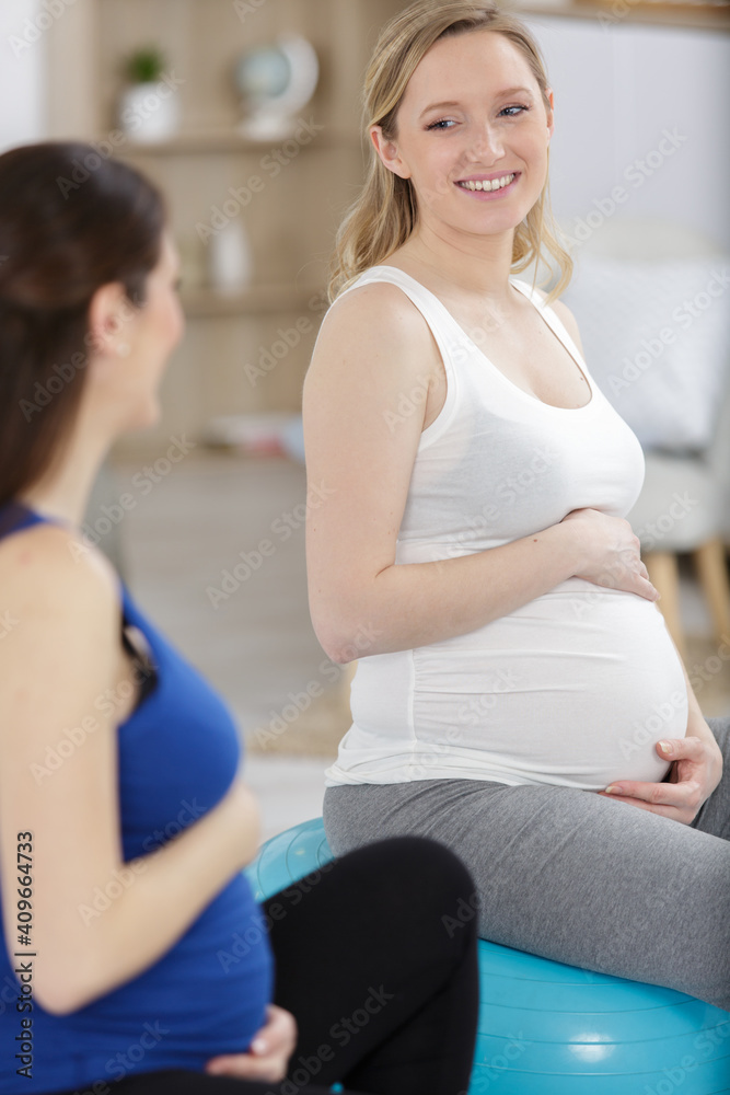 two pregnant women while exercising with a fitness ball