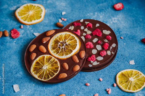 Diet dark chocolate without sugar based on cocoa and stevia with the addition of freeze-dried berries, nuts and fruits. Top view on blue background photo