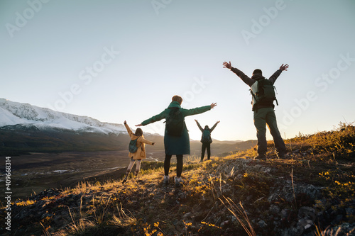 Happy hikers with raised arms in sunset mountains
