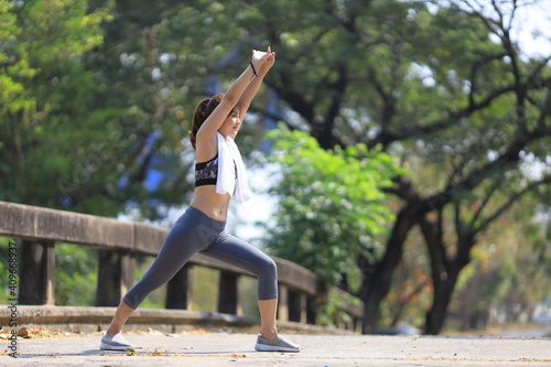 Asian woman in sportswear doing stretching before jogging in the outdoor park with copy space © Akarawut