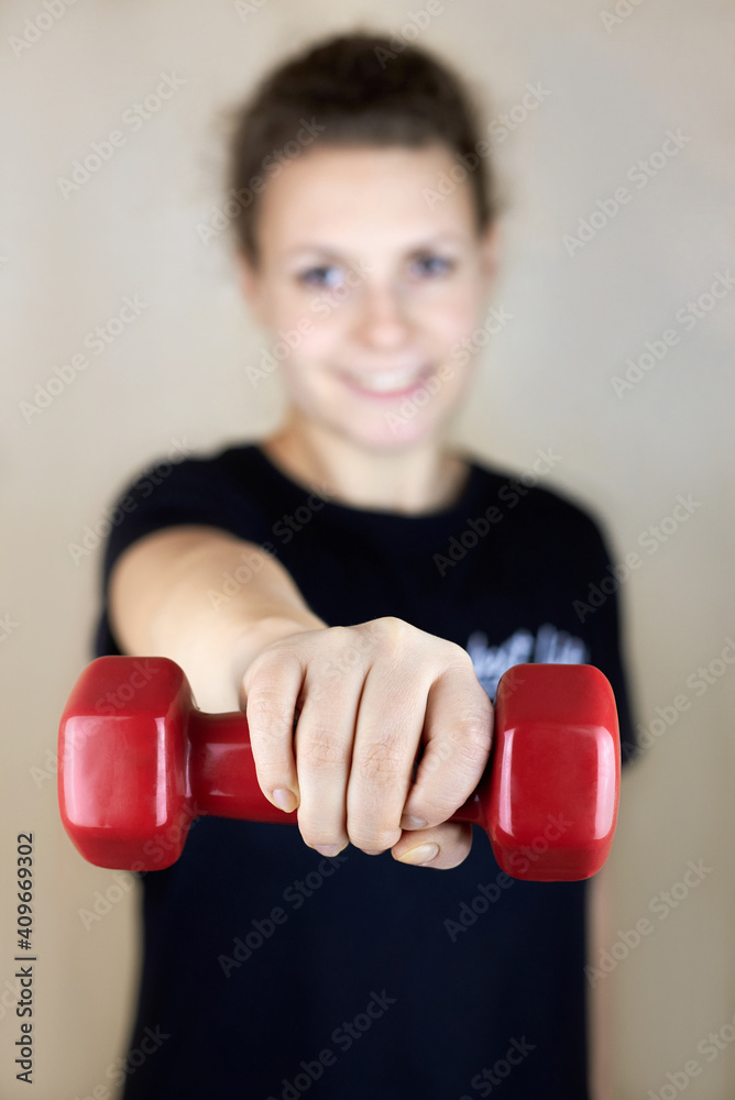Woman holding a dumbbell in front of herself.