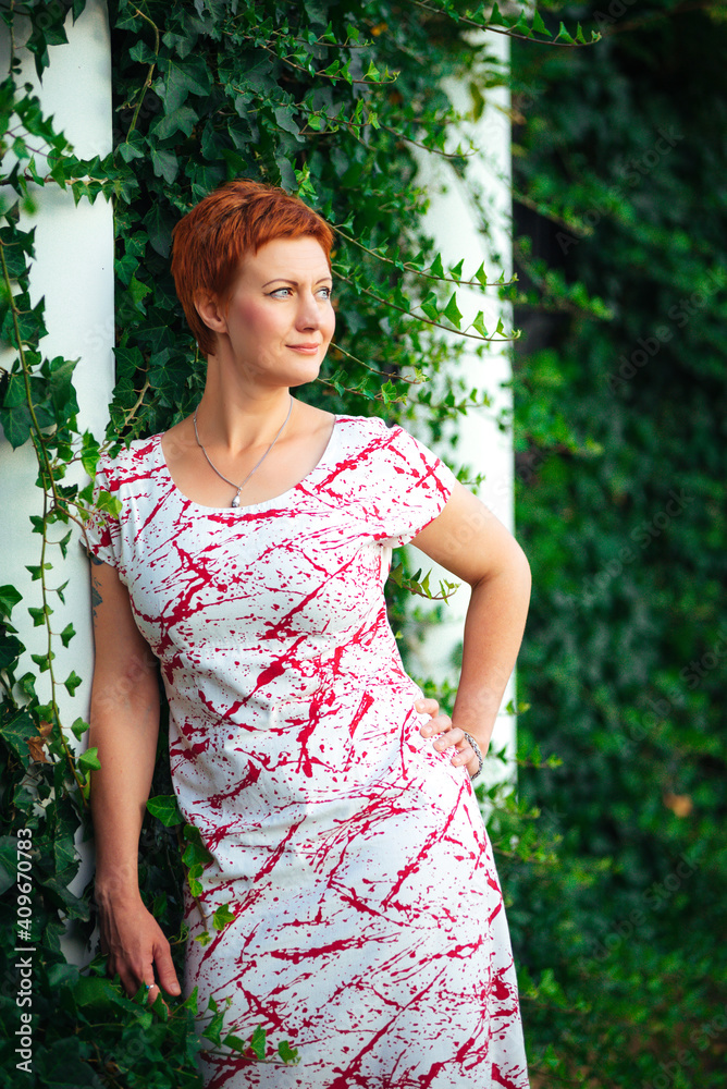 Beautiful, gorgeous and sexy red-haired woman posing near the wall of green foliage and leaves in the garden, glamour and vogue outdoor summer photoshoot on nature Beautiful, gorgeous and sexy red-haired woman posing near the wall of green foliage and leaves in the garden, glamour and vogue outdoor summer photoshoot on nature
