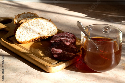 A cup of tea with bread and kalbasa on a wooden board. photo