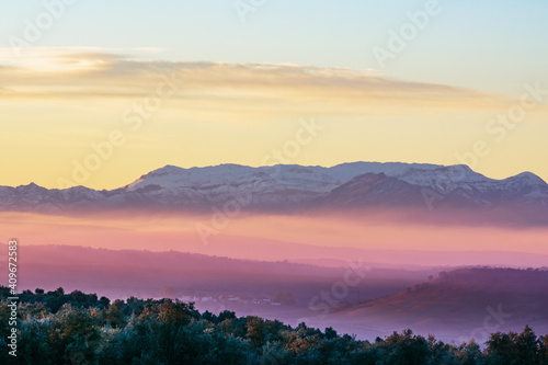 Landscape of Sierra Morena de Jaen, located in the northern region of Linares, with snow-capped mountains and the morning mist colored by the sun. photo