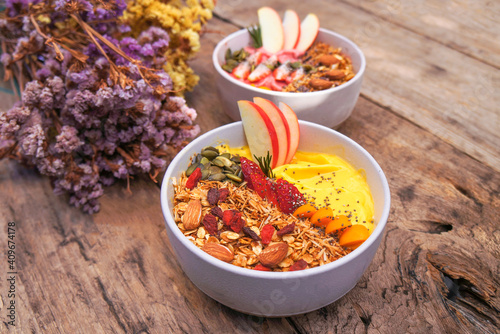 Healthy pineapple  mango and strawberry smoothie bowl with granola  seeds   almond fresh strawberries and fresh apple in White ceramic bowl.detox  vegetarian  vegan food concept 