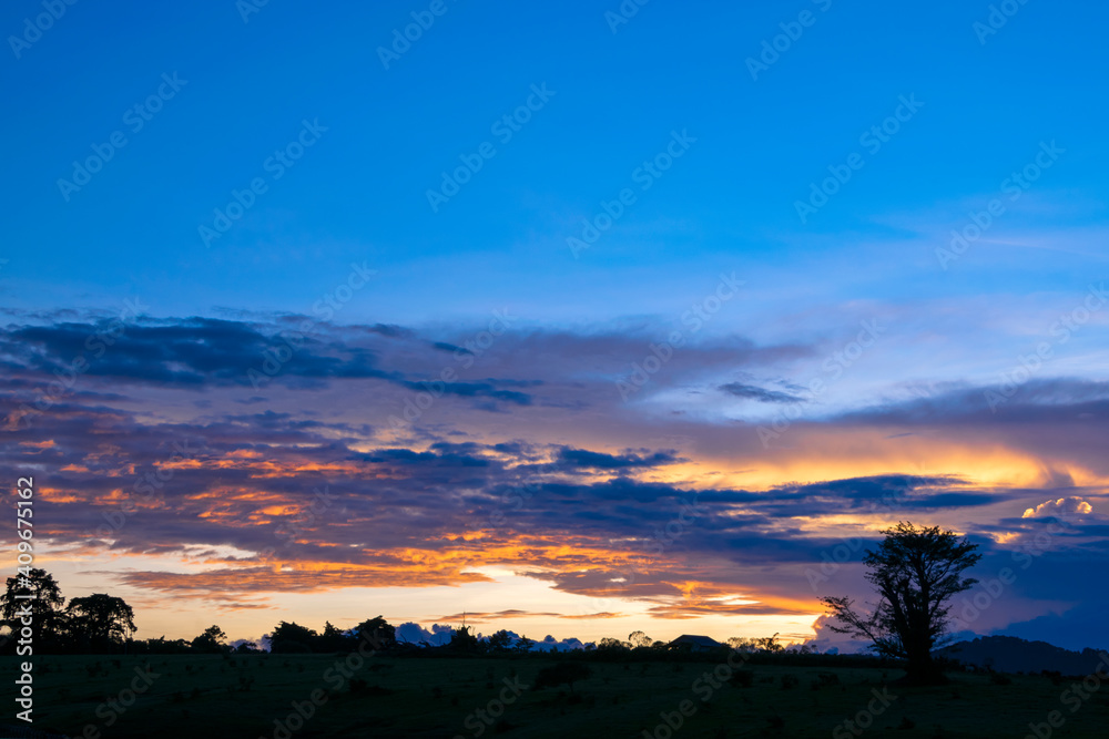 Sunset in rural Guatemala, open space and sky with dramatic clouds, silhouette of tropical colored trees, space for creation and inspiration.