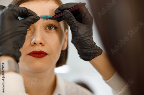 Professional brow master is doing her job for beautiful caucasian woman at beauty salon