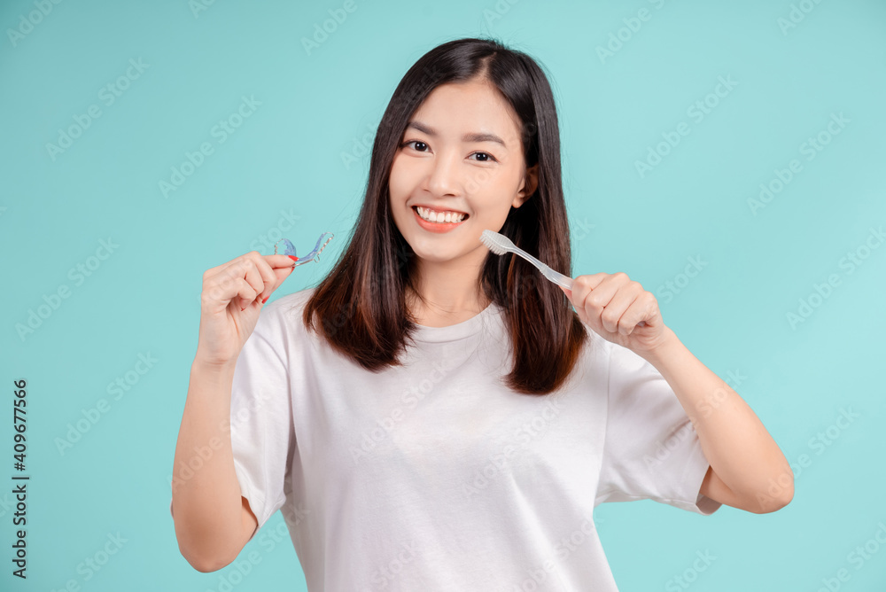 Dental Beautiful smiling of young asian woman with retainer braces and toothbrush for white teeth increase confidence for healthy on blue background isolated, Happiness teenager facial expression. Dental Beautiful smiling of young asian woman with retainer braces and toothbrush for white teeth increase confidence for healthy on blue background isolated, Happiness teenager facial expression.