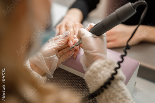 Professional manicure master is doing nails for happy client in beauty salon