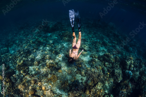 Woman in bikini dive to corals underwater in tropical sea