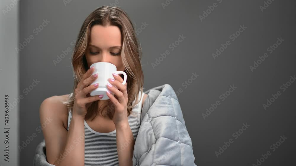 Female with fresh skin drinking coffee wrapped in blanket. Medium close up shot on 4k RED camera Female with fresh skin drinking coffee wrapped in blanket. Medium close up shot on 4k RED camera