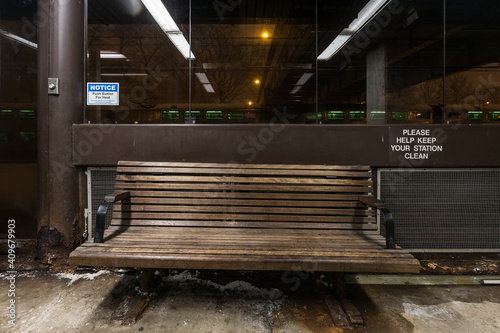 Fototapeta Naklejka Na Ścianę i Meble -  Empty bench in covered waiting area for passenger trains at night in downtown Chicago