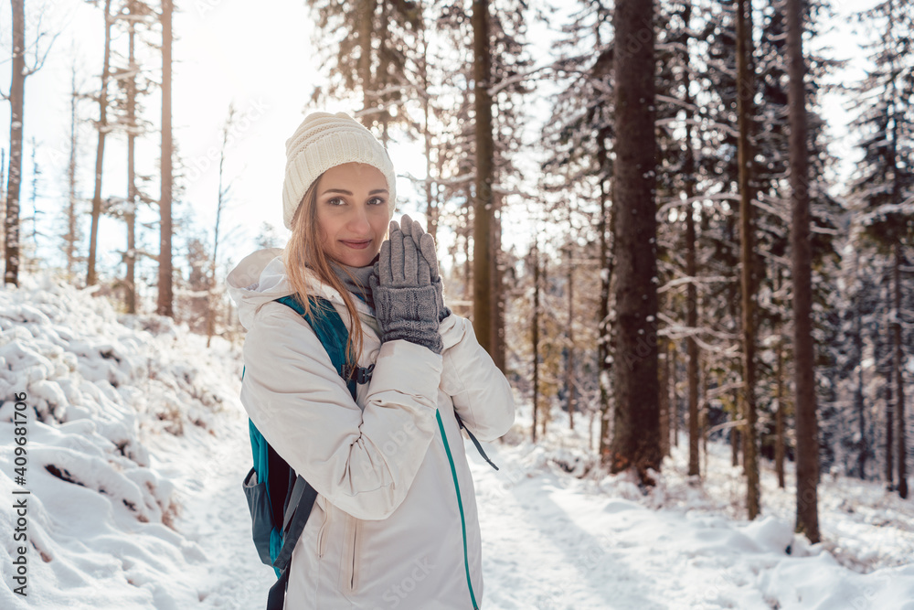 Woman on winter hike enjoying the sunset in the forest