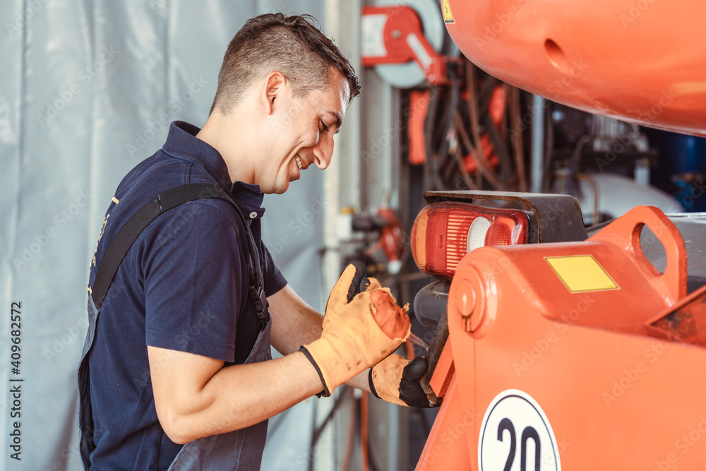 Foto de Technician for farm machinery doing maintenance work do Stock