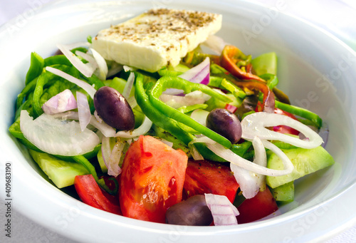 Greek Nicosia salad on a plate with feta cheese, olives, tomatoes and other fresh vegetables. 