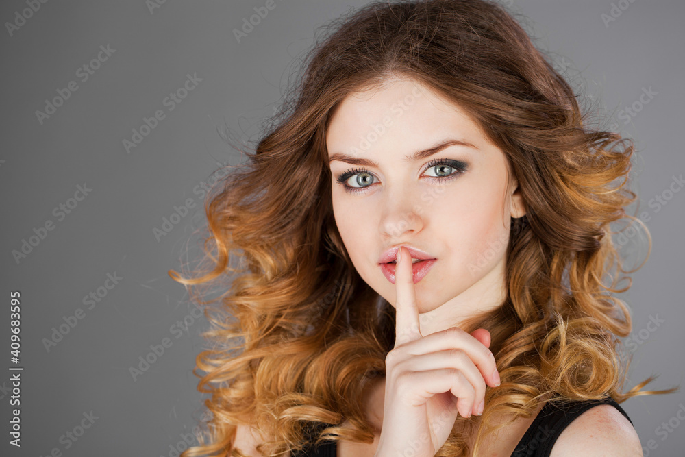 Woman has put forefinger to lips as sign of silence Woman has put forefinger to lips as sign of silence