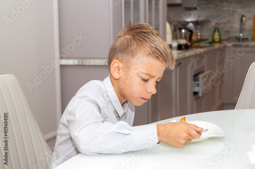 boy in white shirt eat eggs in dining room with modern kitchen in background