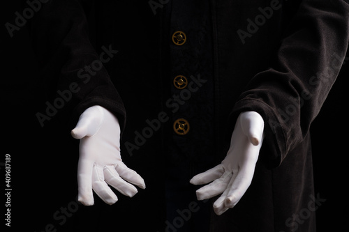 Hand gestures. Show something with your hands, open palms, announcement of the start of the show. Showman or magician illusionist in white gloves on a black background.