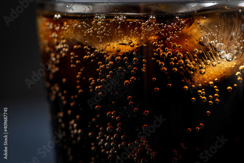 glass of coca cola with ice on a black background, closeup