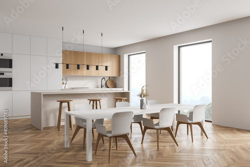 Modern kitchen interior with white walls, a wooden parquet floor and white countertops. A long table with chairs near it. 3d rendering