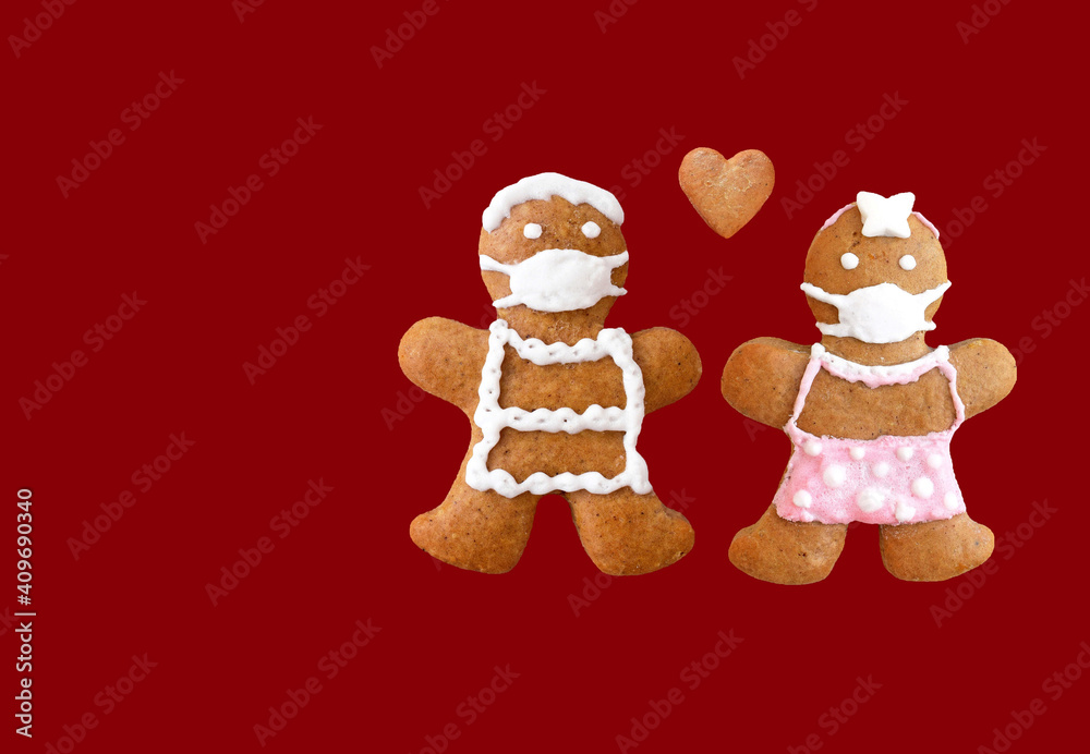 Cute gingerbread couple with protective face masks and heart isolated on red background. Original love concept, coronavirus time. Romantic greeting card, copy space for text Cute gingerbread couple with protective face masks and heart isolated on red background. Original love concept, coronavirus time. Romantic greeting card, copy space for text