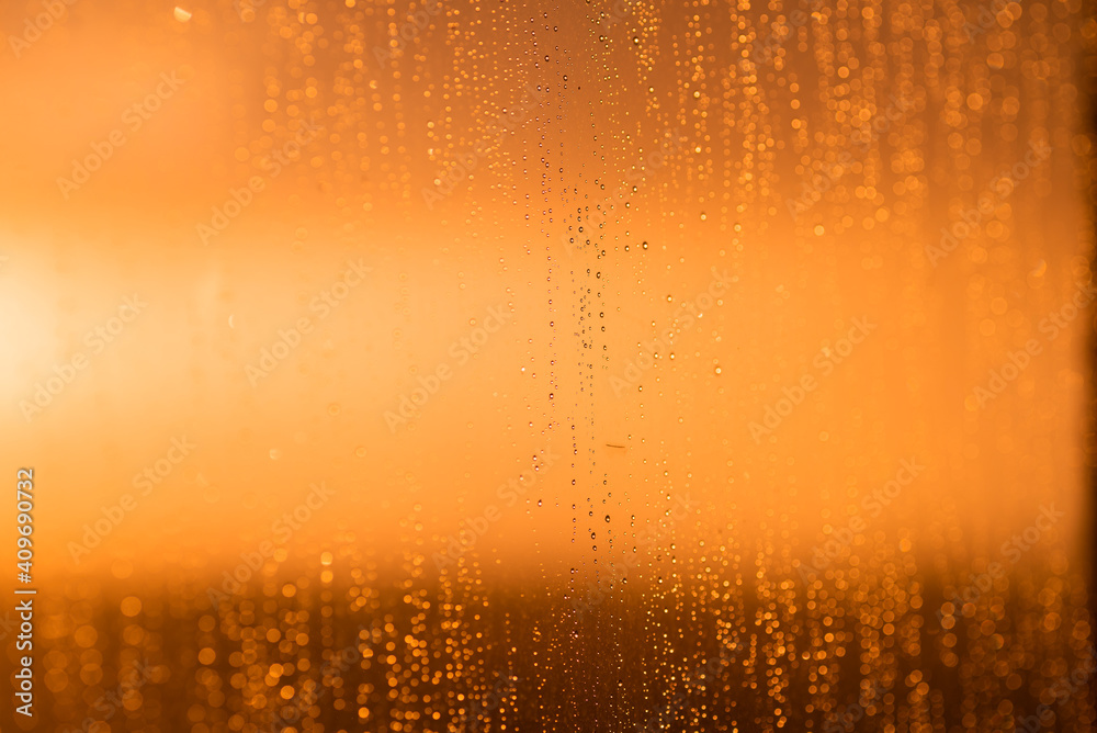 Drops on the glass against the background of an orange sunset