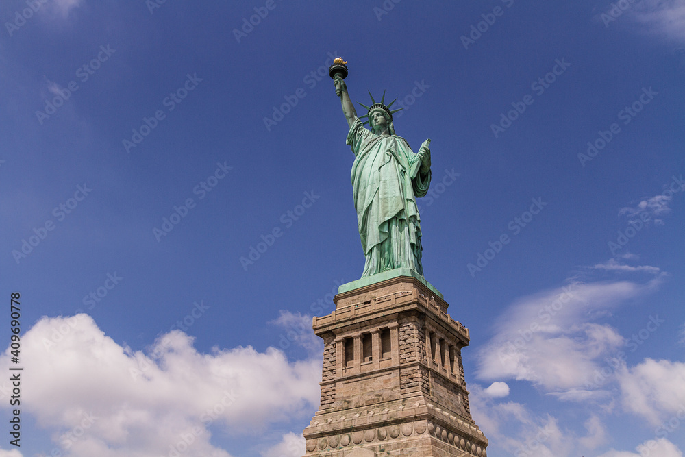 Statue of Liberty in Liberty Island, New York City, with blue cloudy sky in the background
