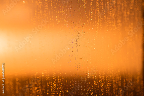 Drops on the glass against the background of an orange sunset