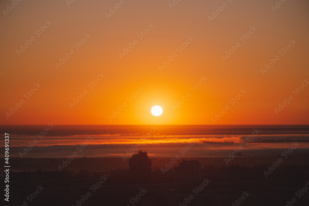 Beautiful orange sunset over the city of Ryazan in summer. Sunrise over the city in the fog in summer