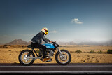 Man seat on the motorcycle on the desert road.