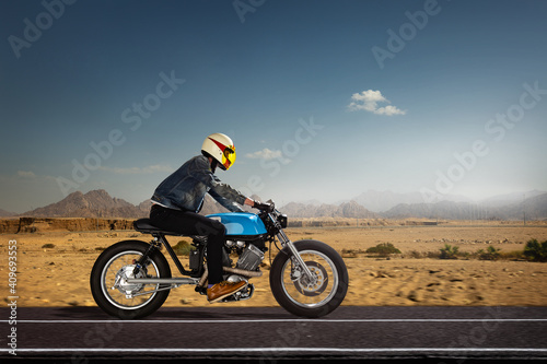 Man seat on the motorcycle on the desert road.
