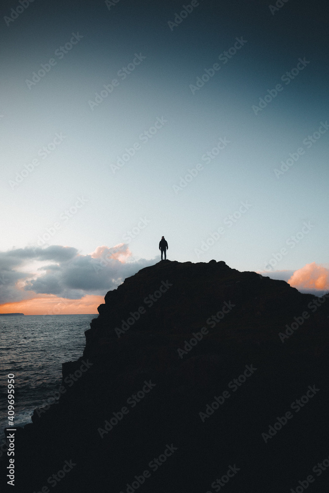 person on hill at sea sunset
